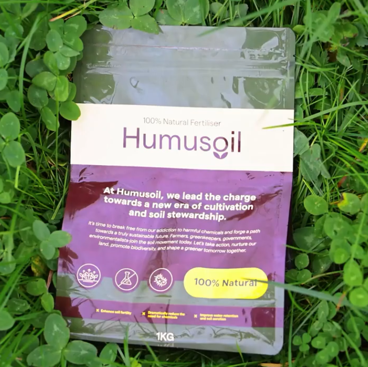 A bag of Humusoil 100% Natural Fertiliser lying on green grass with clover.
